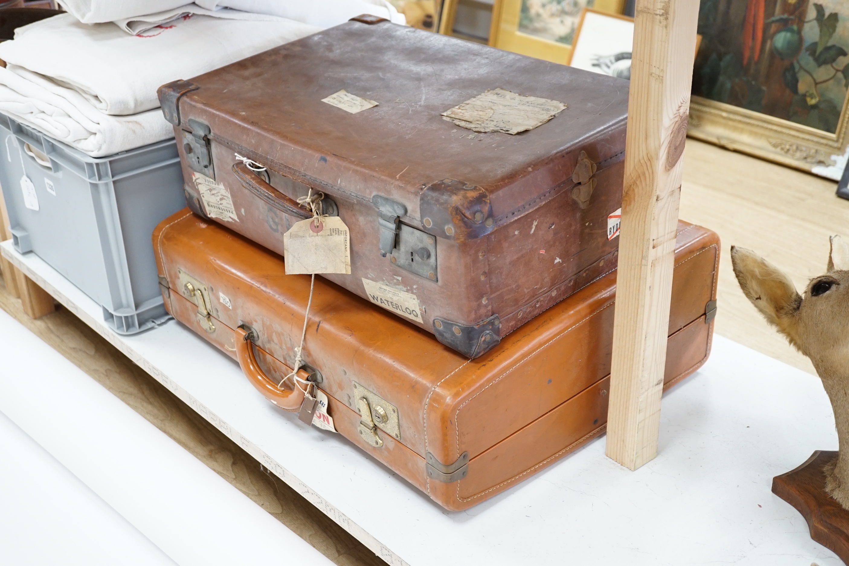 Two vintage suitcases with various labels including British Railways Waterloo, the largest 61cm wide